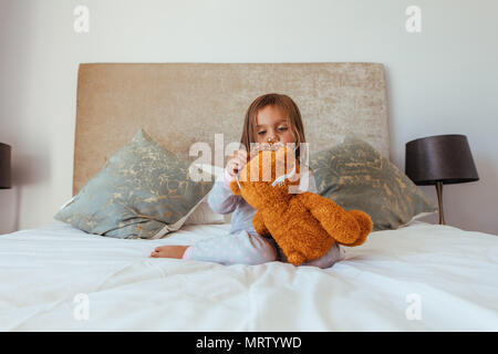 Cute little baby girl putting a crown on her teddy bear. Innocent girl child playing with her soft toy.