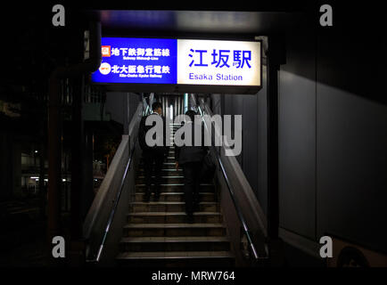 Osaka, Japan - May 27, 2018: Businessmen walking up the stairs to Esaka Station at night Stock Photo