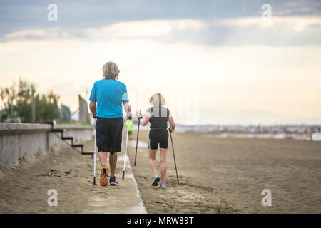 Senior couple nordic waling on the beach. Stock Photo