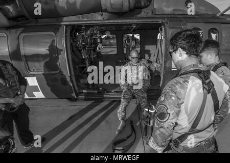 U.S. Army Sgt. Timothy Witts, a Black Hawk crew chief, briefs New Jersey Task Force One members on the hoist system during joint training at Joint Base McGuire-Dix-Lakehurst, N.J., June 28, 2017. (U.S. Air National Guard photo by Master Sgt. Matt Hecht/Released) Stock Photo