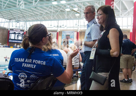 Mrs. Ricki Selva, right, wife of U.S. Air Force Gen. Paul J. Selva, Vice Chairman of the Joint Chiefs of Staff, center, speaks with a Team Air Force family member during the swimming competition of the 2017 Department of Defense (DoD) Warrior Games at the University of Illinois, Chicago, Ill., July 8, 2017. The DoD Warrior Games are an annual event allowing wounded, ill and injured service members and veterans to compete in Paralympic-style sports. (DoD Photo by U.S. Army Sgt. James K. McCann) Stock Photo