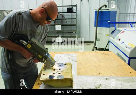 Tobyhanna Army Depot is a United States Army logistics and maintenance facility located in Tobyhanna, Pennsylvania. The archival image documents testing of a high-power paint removal system identified as a Class 4 laser manufactured by Adapt Laser Systems, utilizing fiber optic delivery for surface stripping and industrial safety evaluation. Stock Photo