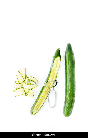 Whole cucumber and cucumber shavings on white background with lots of copy space. Stock Photo