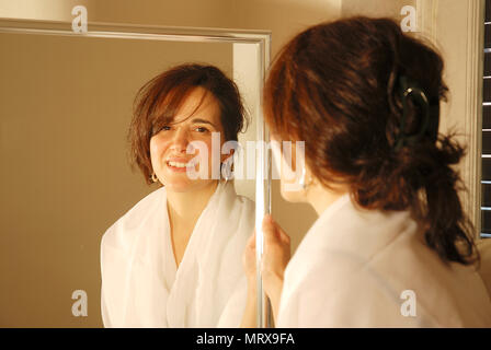 Portrait of woman looking at the camera from her image reflected on a mirror. Stock Photo