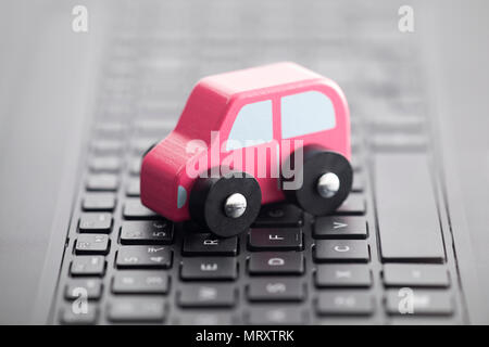 Wooden car toy on laptop keyboard Stock Photo