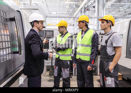 Manager and workers at plant near CNC machines Stock Photo