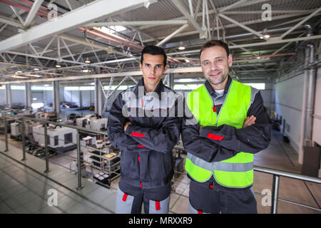 Team of two workers in uniform standing at background of CNC factory Stock Photo