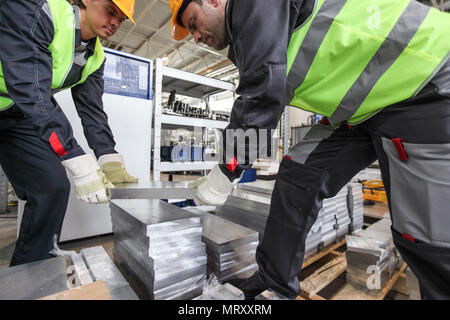 Workers taking aluminium billet at CNC machine shop Stock Photo