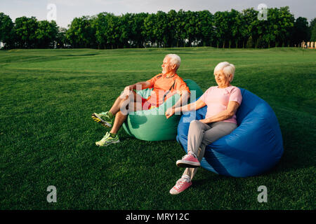 Senior couple sitting on beanbags on grass Stock Photo