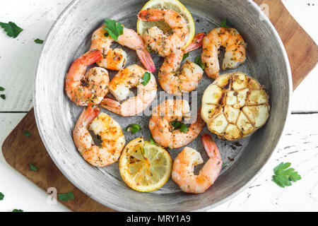 Roasted shrimps with lemon, garlic and herbs. Seafood, shelfish. Shrimps Prawns grilled with spices, garlic and lemon on black stone background, copy  Stock Photo