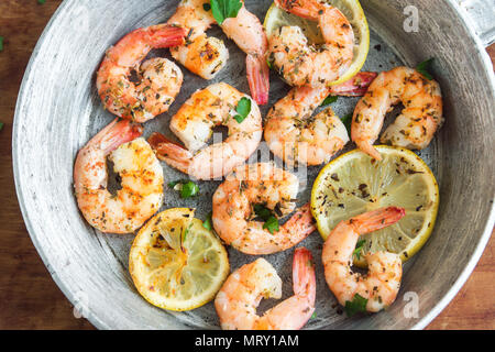 Roasted shrimps with lemon, garlic and herbs. Seafood, shelfish. Shrimps Prawns grilled with spices, garlic and lemon on black stone background, copy  Stock Photo