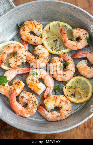 Roasted shrimps with lemon, garlic and herbs. Seafood, shelfish. Shrimps Prawns grilled with spices, garlic and lemon on black stone background, copy  Stock Photo