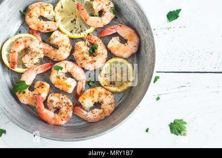 Roasted shrimps with lemon, garlic and herbs. Seafood, shelfish. Shrimps Prawns grilled with spices, garlic and lemon on white background, copy space. Stock Photo