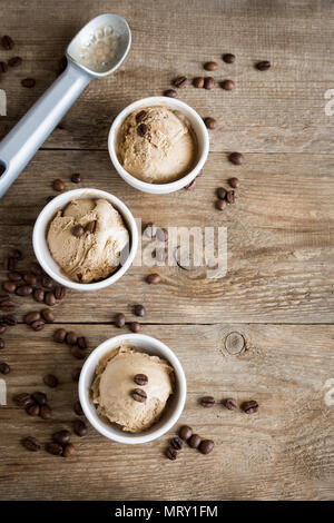 Coffee ice cream on wooden background, top view. Frozen coffee gelato ice cream with coffee beans and cinnamon - healthy summer dessert. Stock Photo