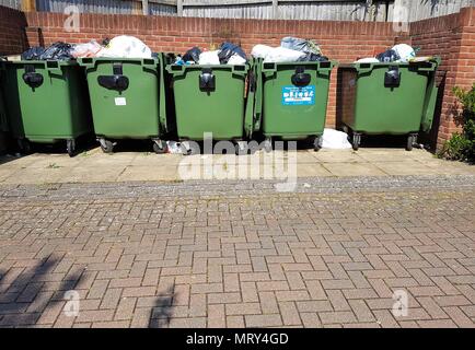 Row of green wheelie bins filled with rubbish Stock Photo