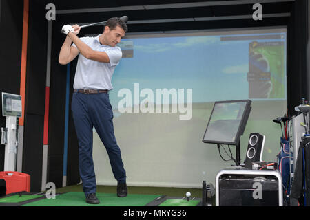 Man practicing golf swing using simulator Stock Photo