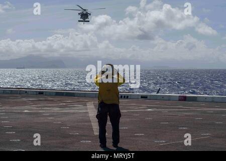 PACIFIC OCEAN (July 16, 2017) Aviation Boatswain’s Mate (Handling) 3rd Class  Esmerelda Hernandez, a native of Corpus Christi, Texas, assigned to the air department onboard the amphibious transport dock ship USS San Diego (LPD 22) directs an MH-60S Sea Hawk, assigned to the “Wildcards” Helicopter Sea Combat Squadron 23, to land on the ship’s flight deck. San Diego is embarked on a scheduled deployment as part of the America Amphibious Ready Group, which is comprised of more than 1,800 Sailors and 2,600 Marines assigned to the amphibious assault ship USS America (LHA 6), the amphibious dock lan Stock Photo