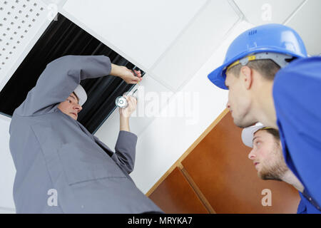 electricians installing ceiling lights in domestic home Stock Photo