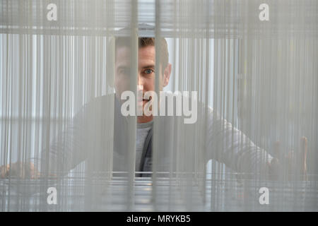 Portrait of man through metal mesh Stock Photo