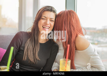 Portrait of two young beautiful girls enjoying together. Two young girl friends having fun in a restaurant laughing, talking and gossiping.Girls talk. Stock Photo
