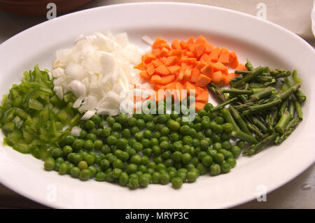 View of a plate with freshly cut vegetables. Carrot, onion, wild asparagus and green pepper. Stock Photo