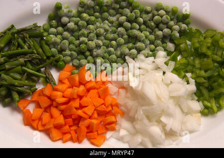 View of a plate with freshly cut vegetables. Carrot, onion, wild asparagus and green pepper. Stock Photo