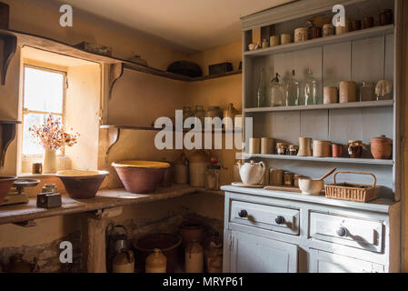Old cooking utensils on shelves and the dresser in the Scullery, the Manor House, Cogges Farm Museum, Witney, Oxfordshire Stock Photo