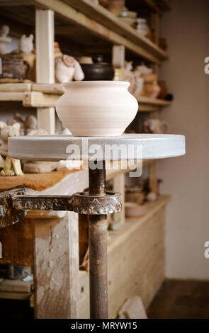 Clay pot close-up in the foreground and shelves with pottery - on the second Stock Photo