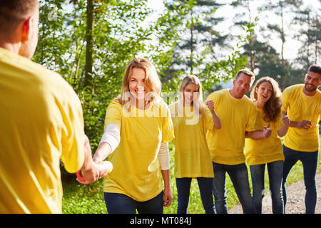 Young team is doing an exercise with baton at the teambuilding workshop Stock Photo