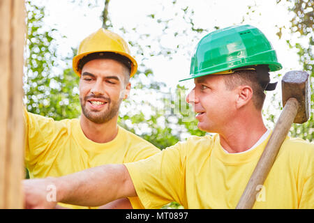 Two men as craftsmen make teamwork while building a house in nature Stock Photo