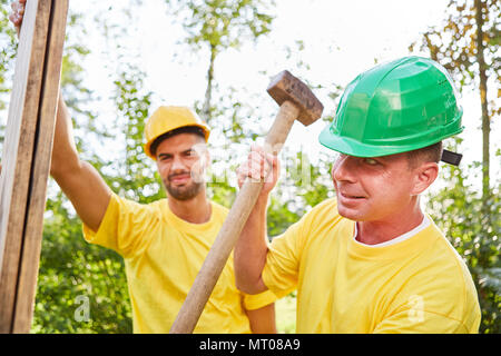 Two craftsmen make teamwork while building a house on the construction site Stock Photo