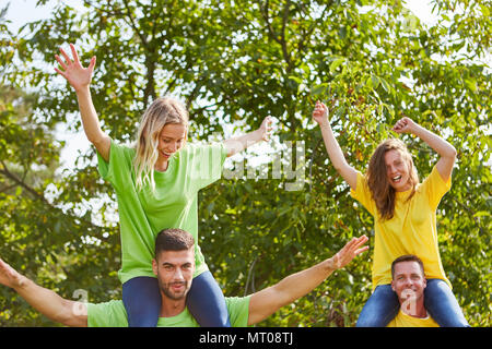 Happy young people in piggybacking game on a teambuilding event Stock Photo