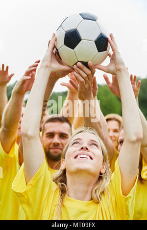 Young sporty team is doing a teamwork exercise together with the football Stock Photo