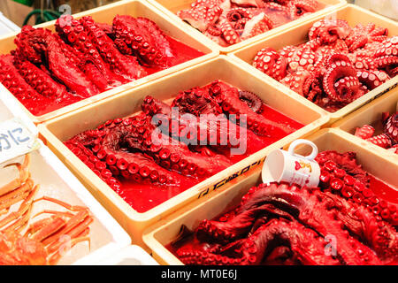 Indoor Omicho Ichiba, Omicho Market, est mid 18th century, largest fresh food market in Kanazawa, Japan. Red and bloodied octopus in boxes on stall. Stock Photo