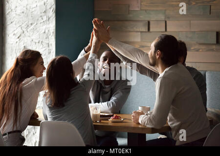 Diverse excited best friends giving high-five together at cafe m Stock Photo