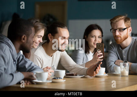 Multi-ethnic group of friends talking and using smartphones at m Stock Photo