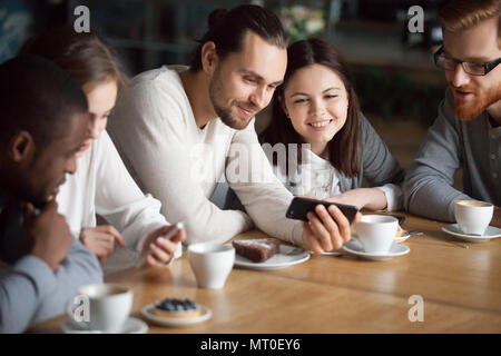 Diverse friends having fun using smartphones hanging together in Stock Photo