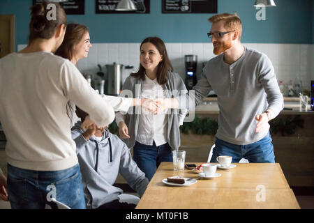 Millennial guy and girl handshaking getting acquainted coming at Stock Photo
