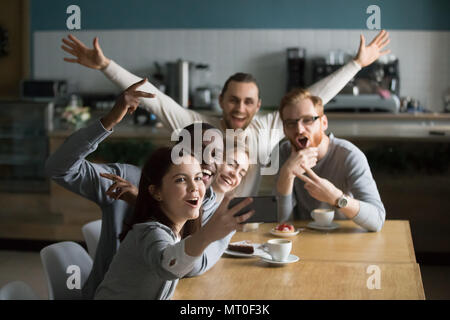 Funny millennial friends taking group selfie on smartphone in ca Stock Photo