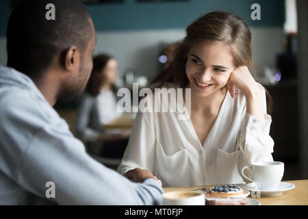 Happy young interracial couple flirting talking holding hands in Stock Photo