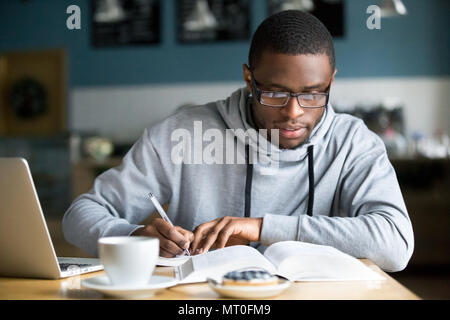 Focused millennial african student making notes while studying i Stock Photo