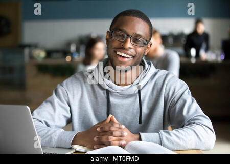 Happy african man sitting at cafe table looking at camera Stock Photo