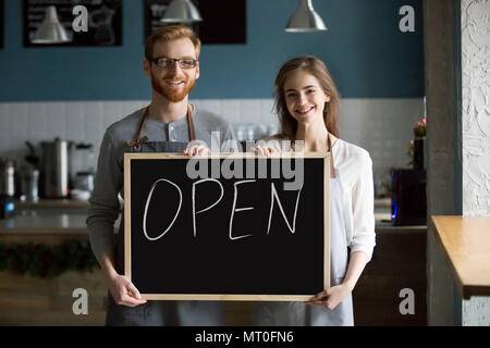 Smiling waiter and waitress holding chalkboard with open sign, p Stock Photo