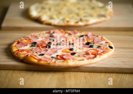 Italian pizzas on wooden boards on restaurant table, pizzeria co Stock Photo