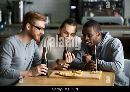 Diverse friends watching online video on smartphone drinking bee Stock Photo