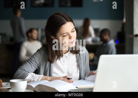 Serious intelligent millennial girl studying in cafe preparing f Stock Photo