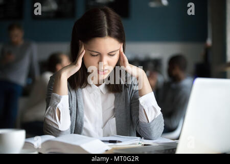 Stressed student having headache preparing for test exam in cafe Stock Photo