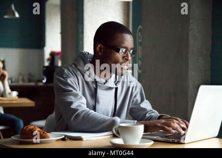 Serious millennial african-american man using laptop sitting at  Stock Photo