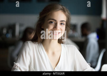 Smiling young pretty lady looking at camera in public place Stock Photo