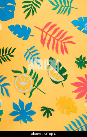 Tropical leaves and fruits pattern on a bright yellow background. Sunny summer colorful flat lay with paper cut outs. Stock Photo